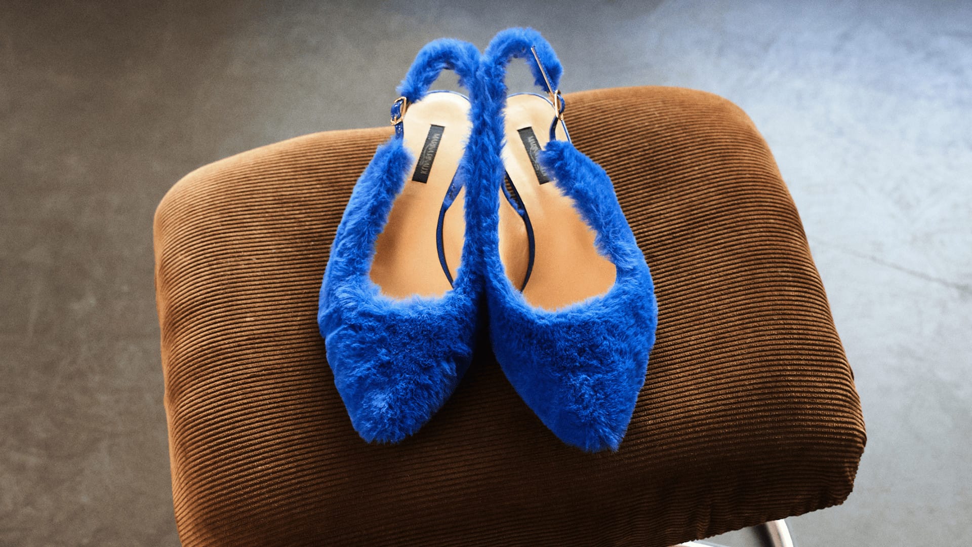 Blue furry slingbacks on brown corduroy stool